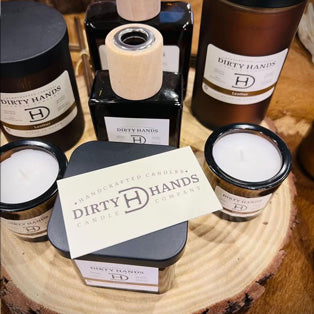 Assorted Dirty Hands candles and diffusers displayed on a wooden slab,this link will open in a new tab.