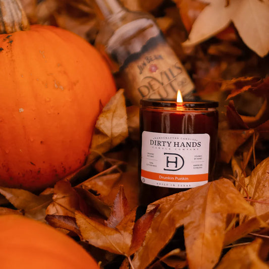 Drunkin Punkin Candle sitting on a bed of fall leaves with a pumpkin