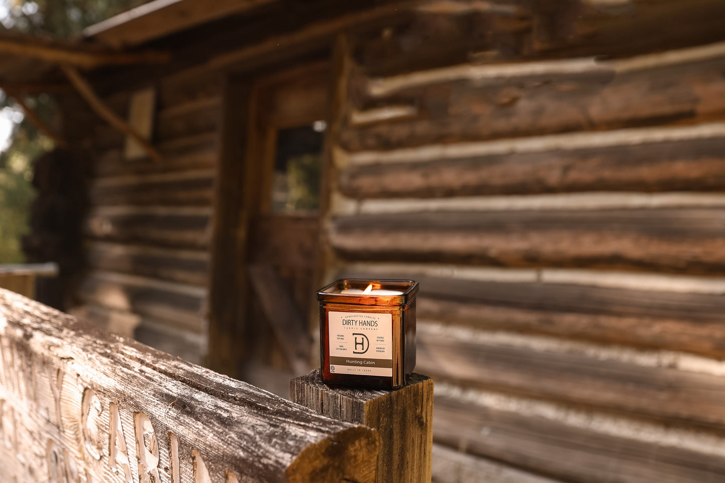 9oz Hunting Cabin Candle sitting on the front porch of a Cabin