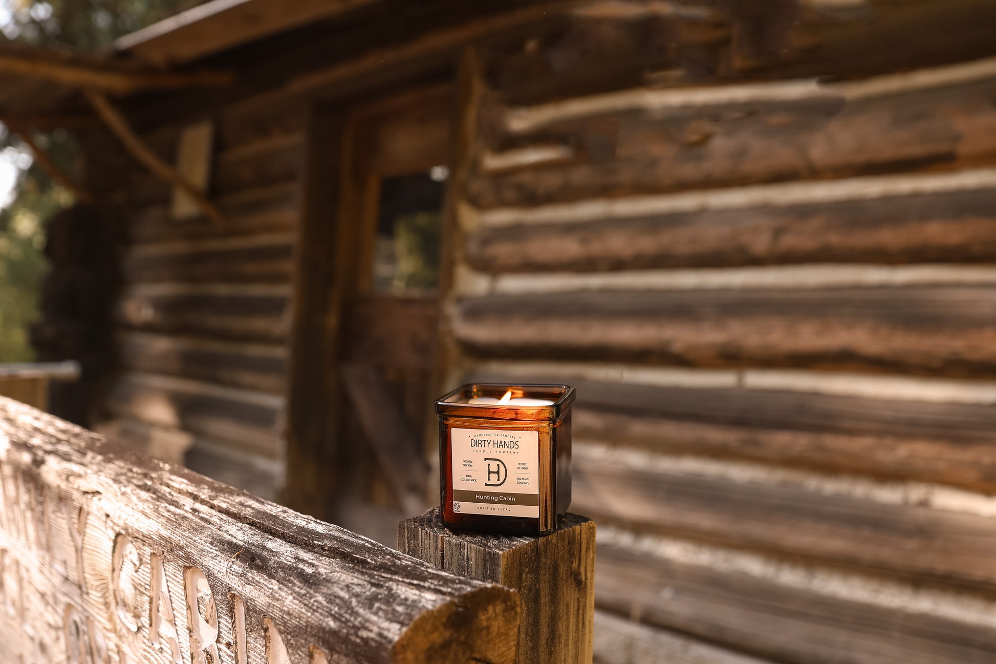 9oz Hunting Cabin Candle sitting on the front porch of a Cabin